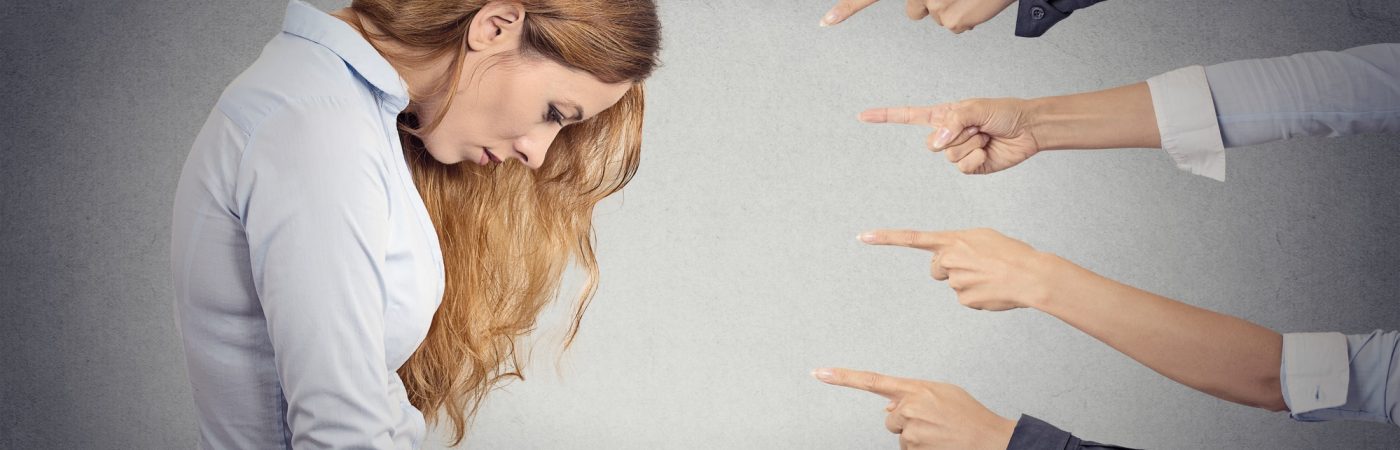 Concept of accusation of guilty businesswoman. Side profile portrait sad upset woman looking down many fingers pointing at her isolated grey office background. Human face expression emotion feeling